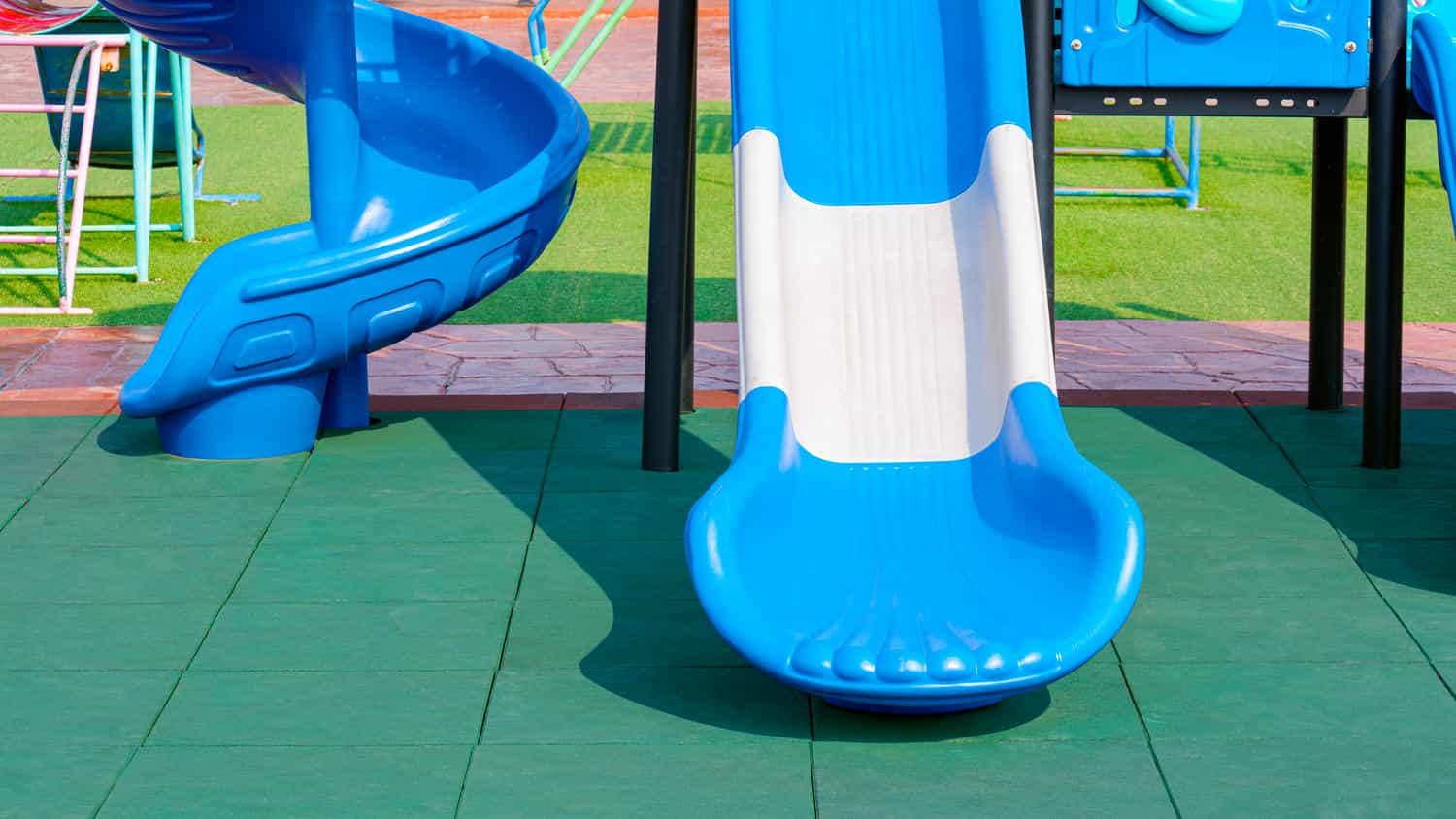 2 slides with playground equipment on green epdm